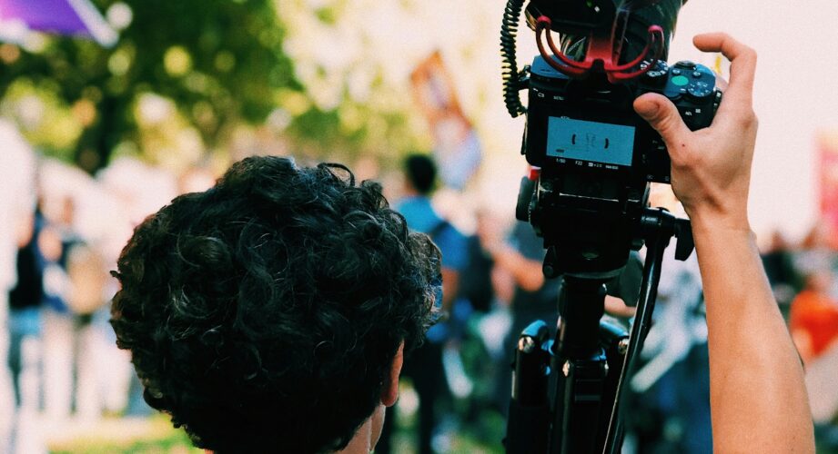 the back of a man holding a camera on a tripod.